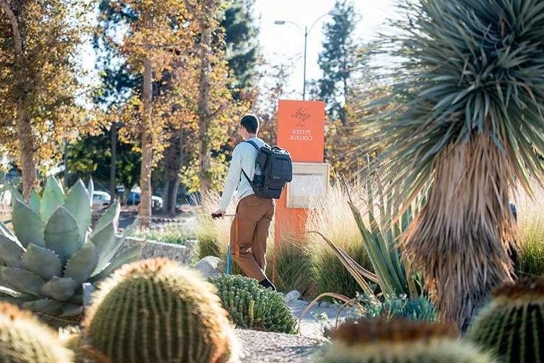 a student scooters through holden garden surrounded by cactus